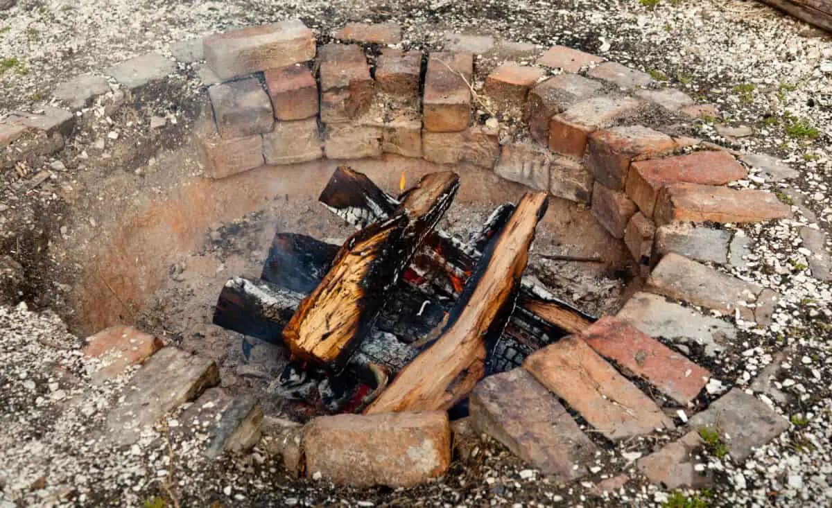 Brick fire pit with wooden logs illustrating lighting your outdoor fire pit.