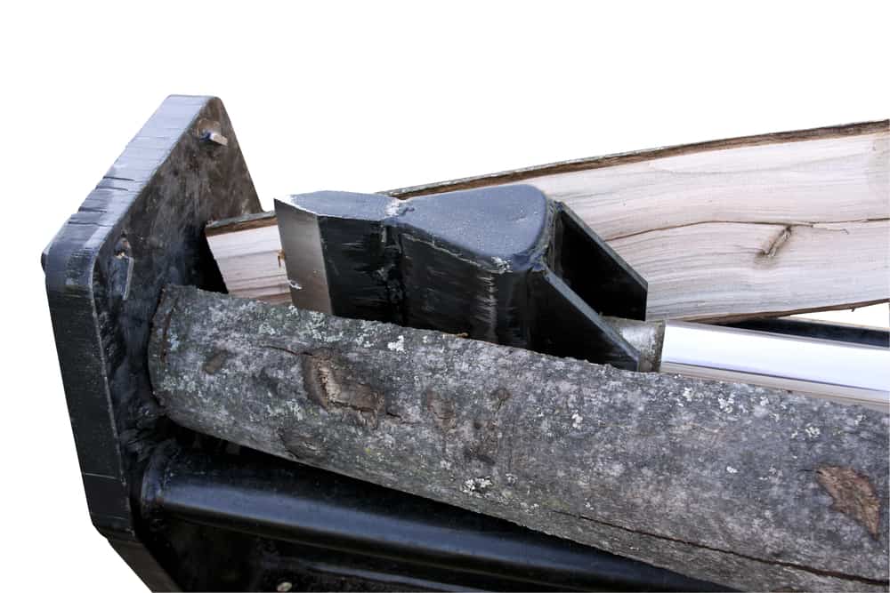 close up of split logs going into splitting wedge with white backdrop