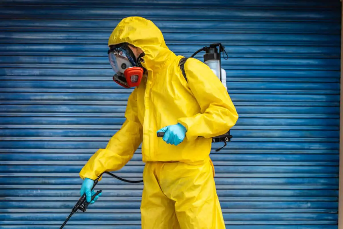 A sanitation worker wearing a mask demonstrating pressure washing safety.