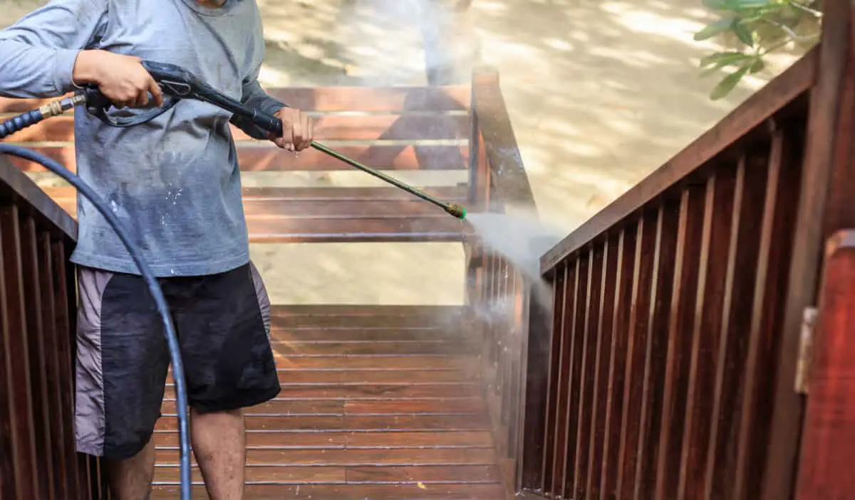 A man cleaning his deck not showing the pressure washer has low pressure. 