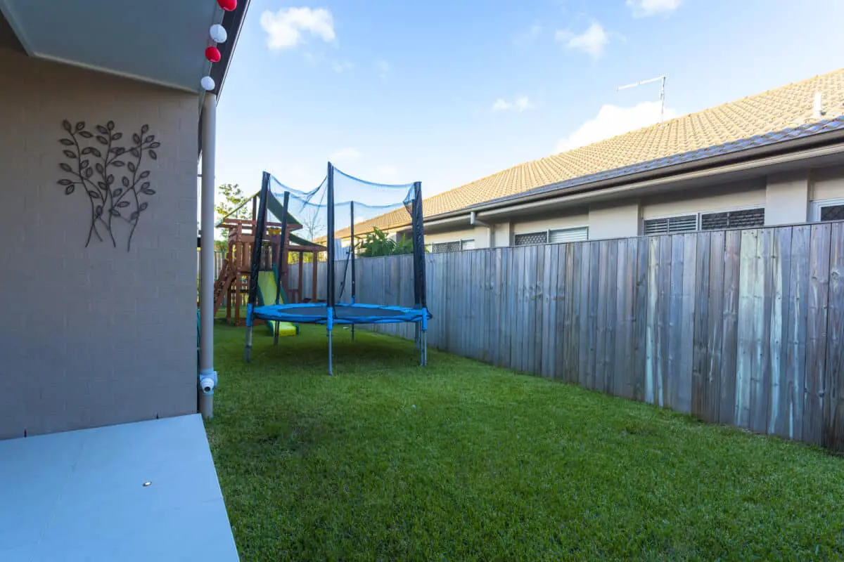 Kids trampoline in small green backyard