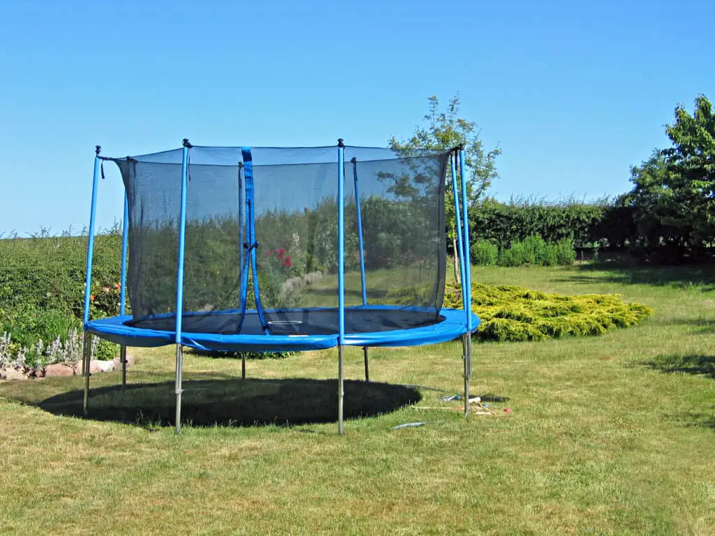 Trampoline with safety net on grass in backyard