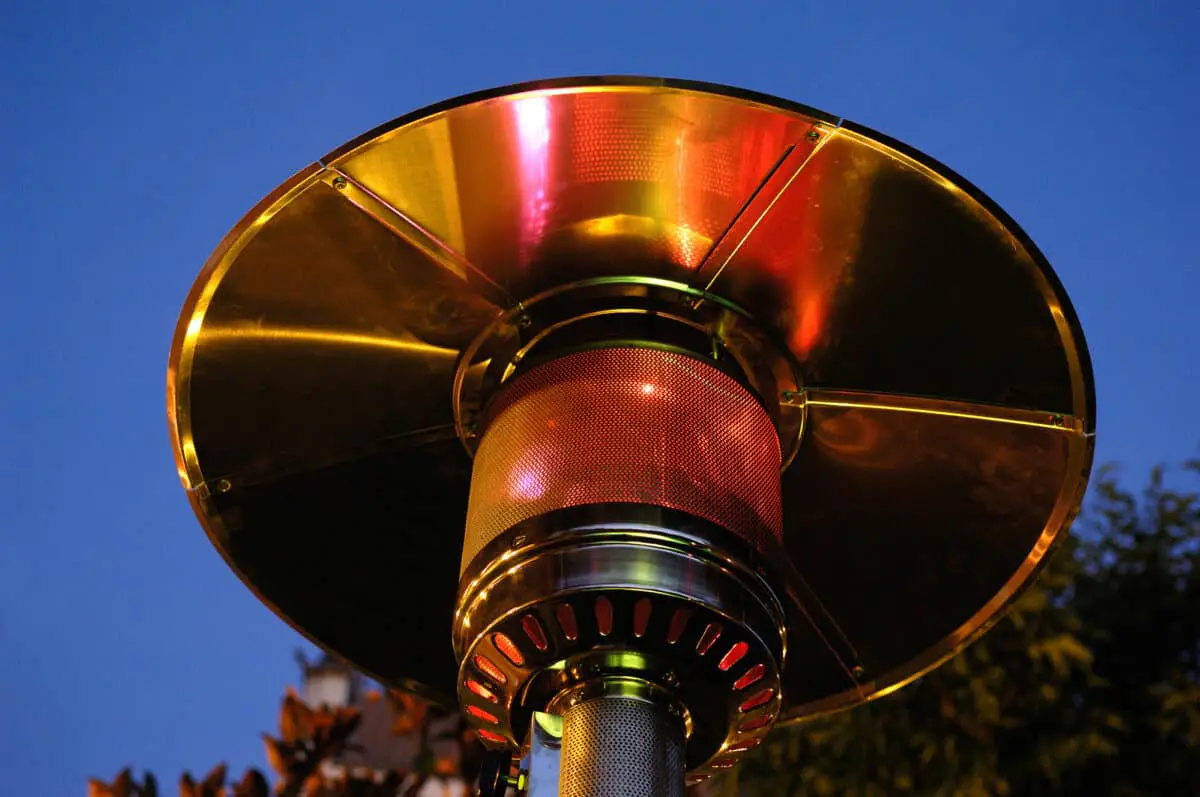 Patio heater in the backyard with a shiny metallic finish as an example of how patio heaters attract bugs.