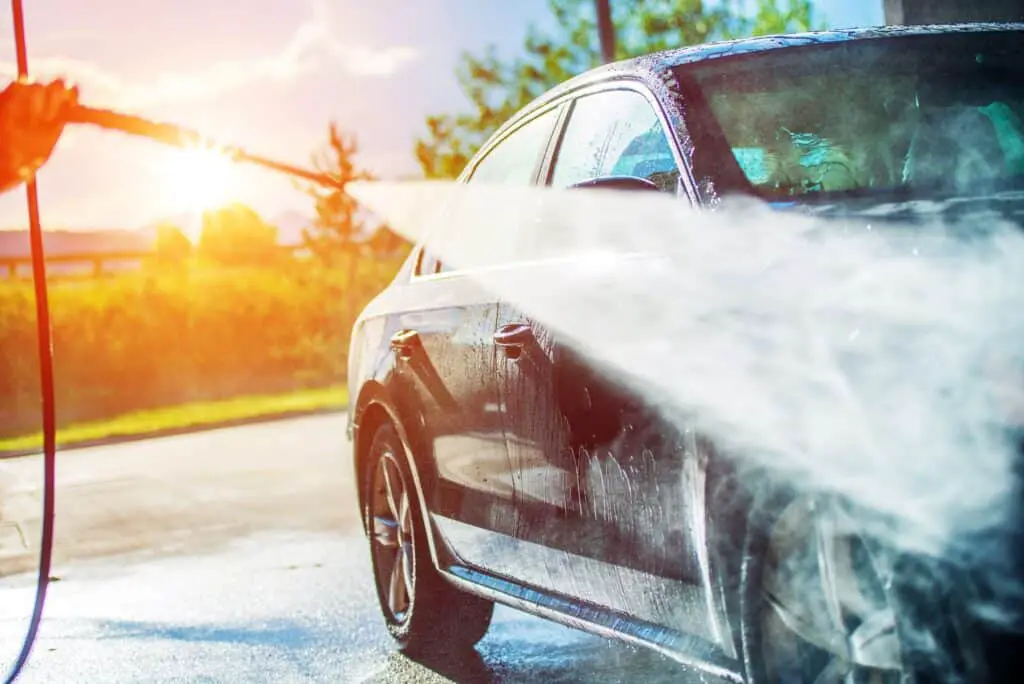 A man showing an example of using a pressure washer on your car.