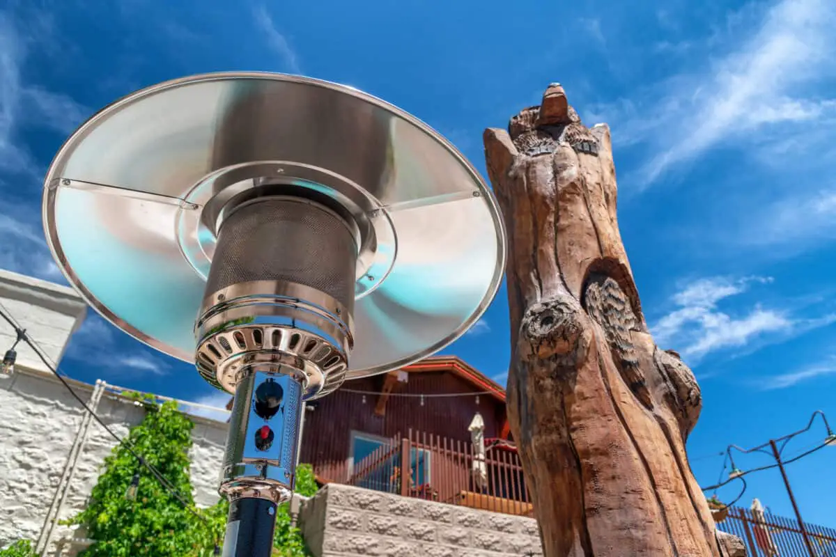 Electric stainless steel metal gas burning outdoor patio heater along with tree trunk on the Route 66 showing patio heater coverage.