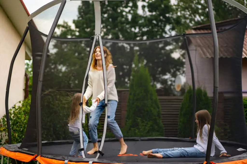 family jumping on trampoline in backyard