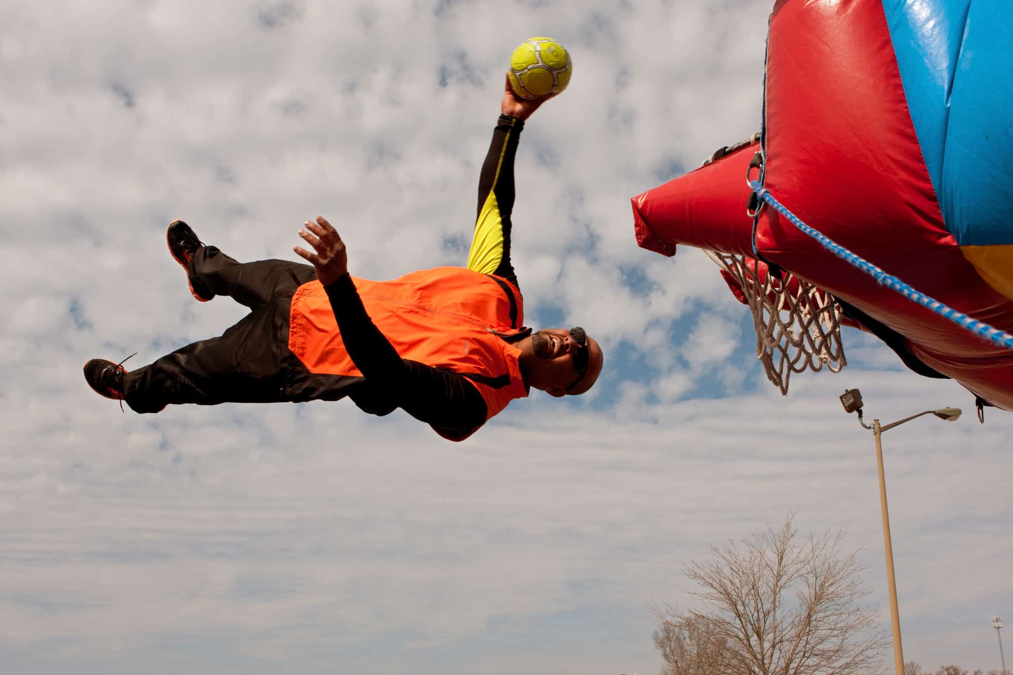 Man slam dunking basketball hoop on trampoline