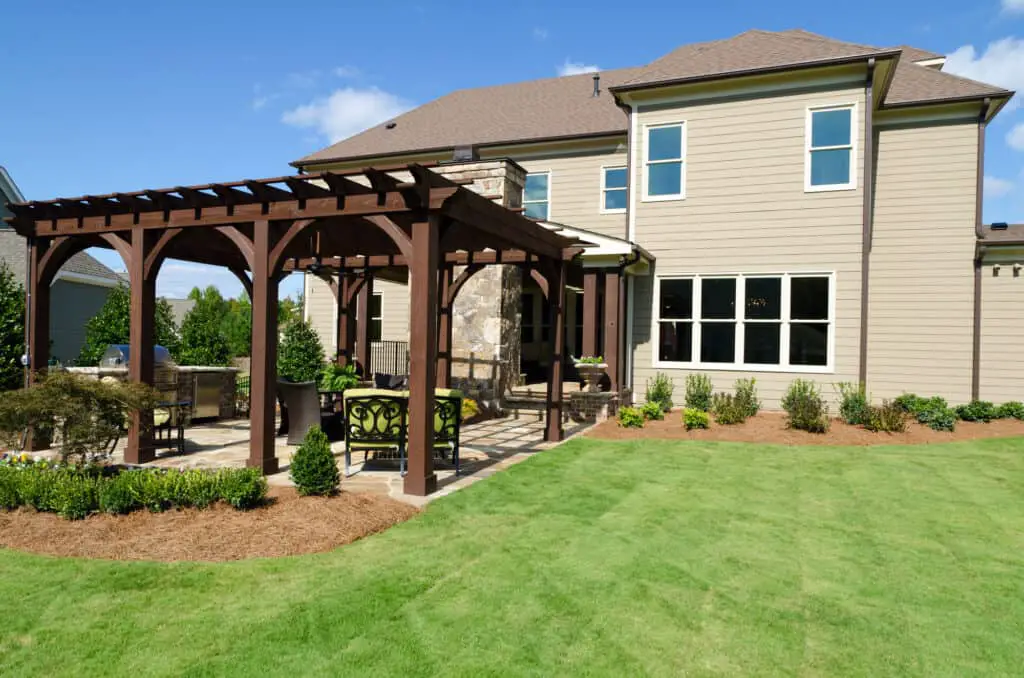 Vinyl pergola in backyard next to house with sun shining