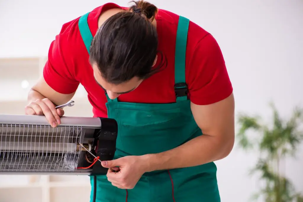 Man in uniform bent over fixing patio heater problems with tools