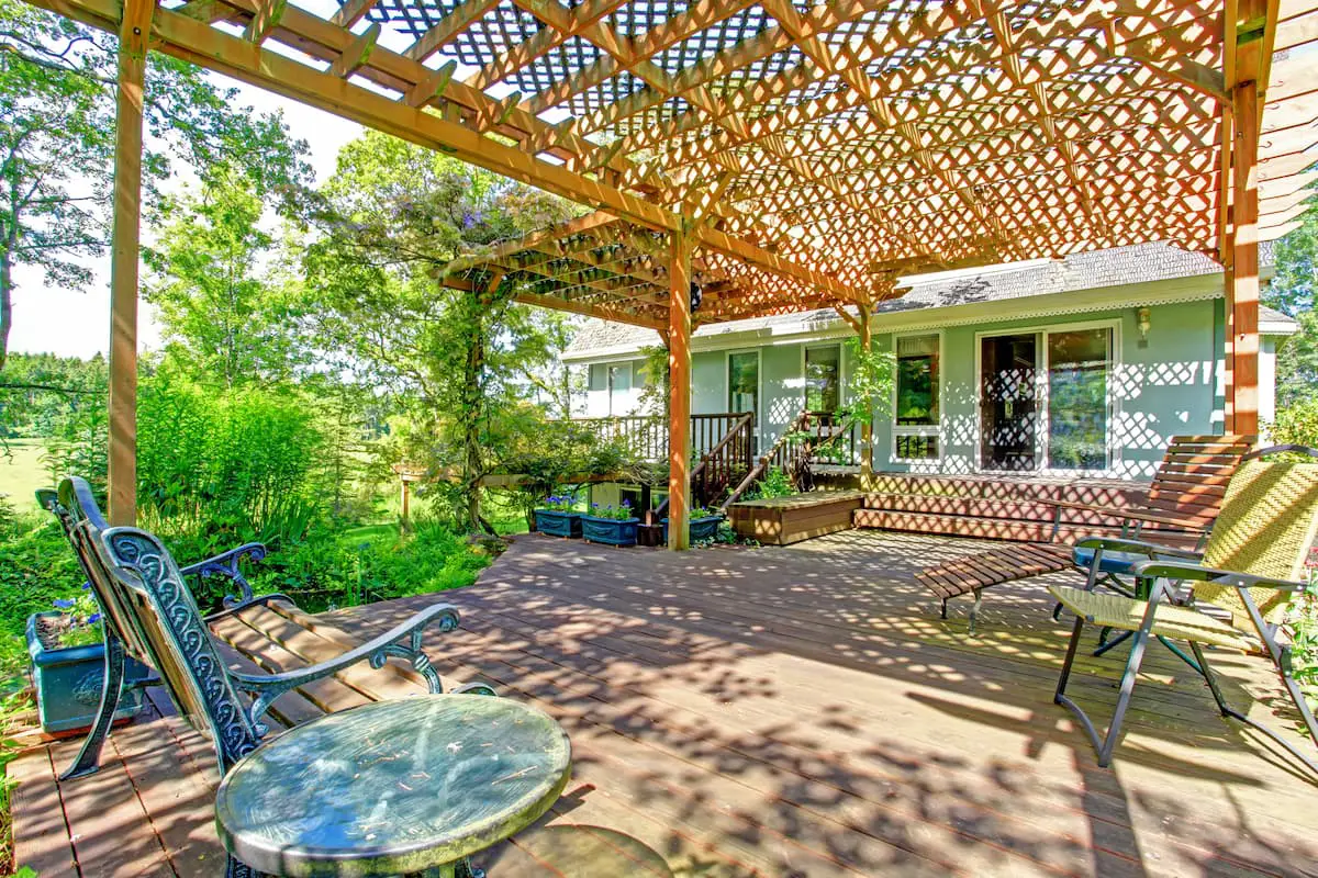 Picture of large backyard patio with excellent shade coverage from a pergola showcasing the many reasons to own a pergola for backyard beauty and shade coverage