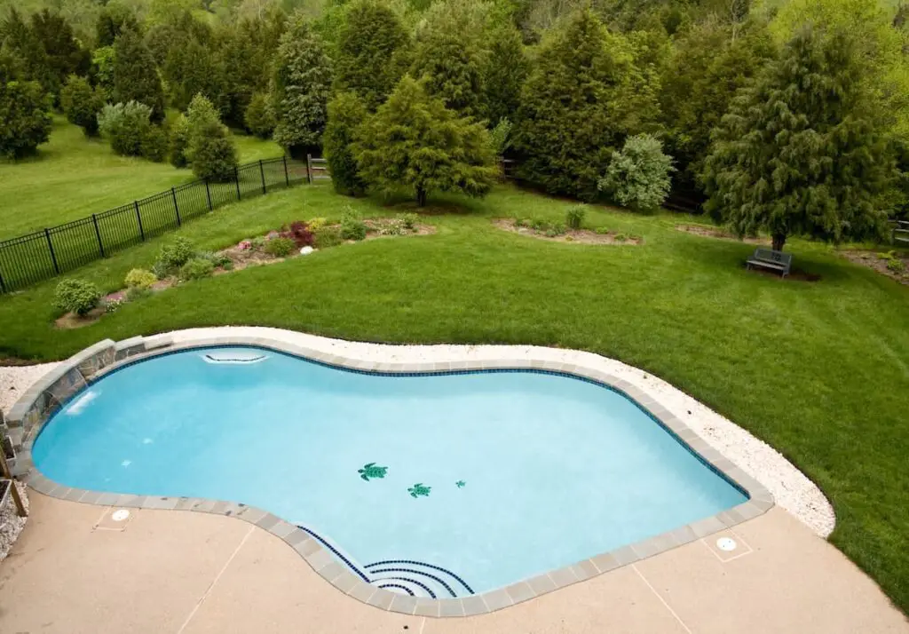 Large pool in backyard with pool water next to the grass