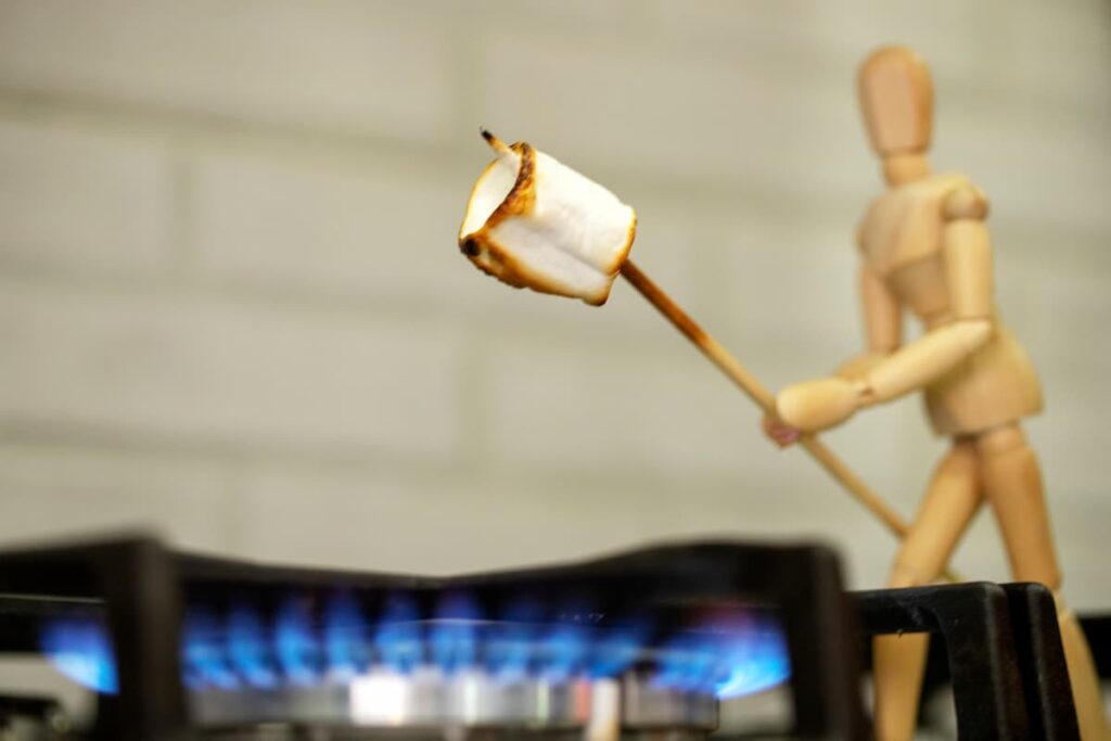 A wooden human figure showing using gas fire pits and roasting marshmallows.