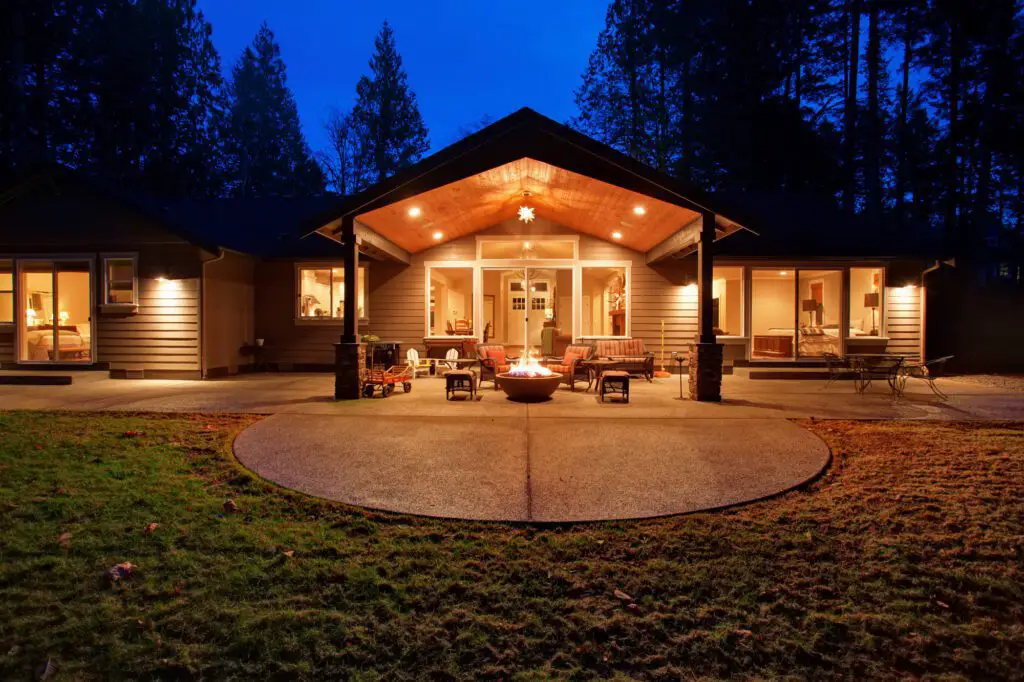 Large back yard with grass and covered patio with firepit.