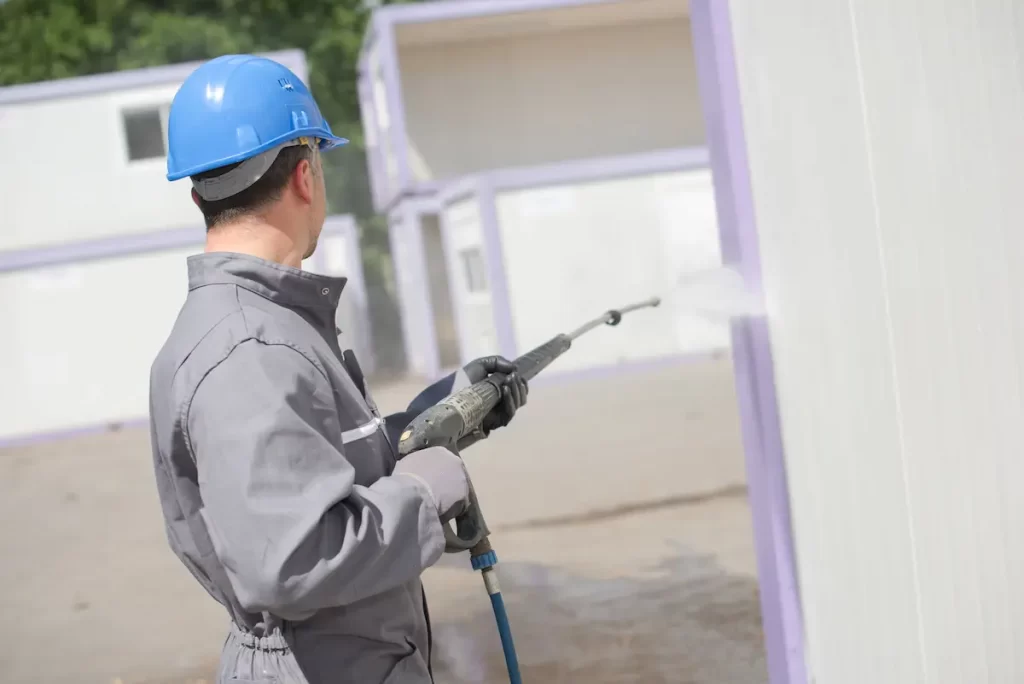 Man using bleach to pressure wash your house.