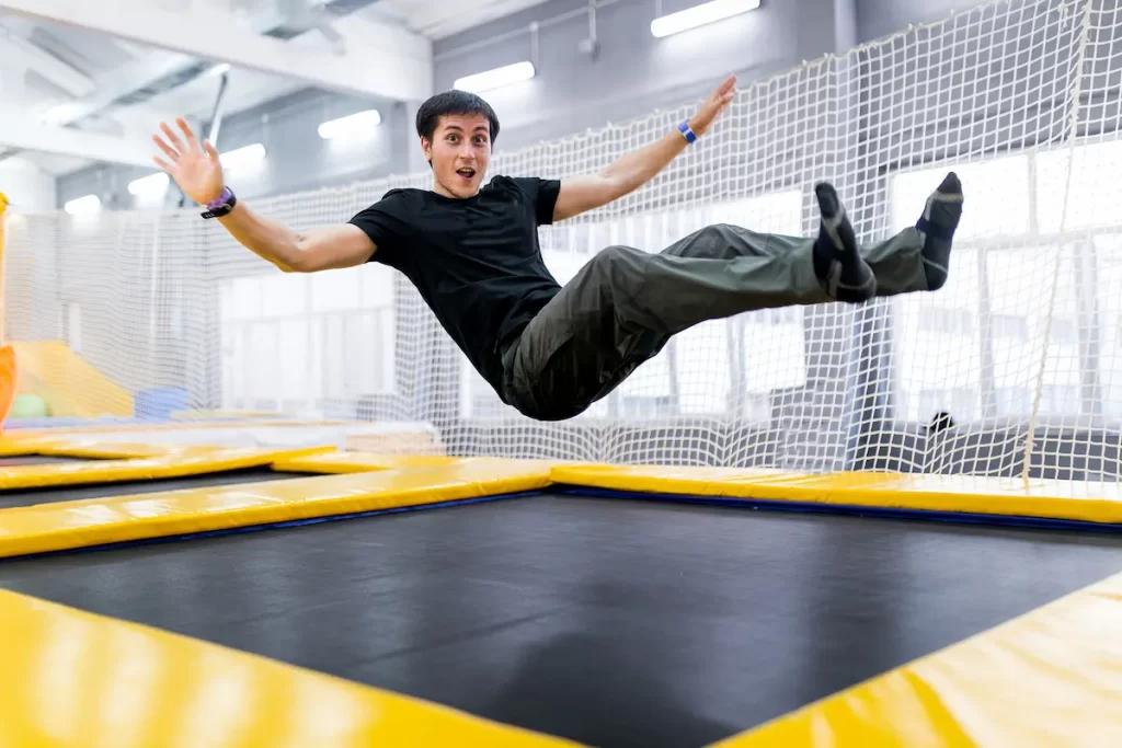 Young man hasa to pee while jumping on trampoline with surprised look on face