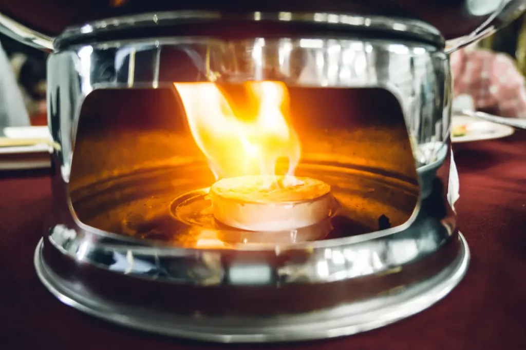 A close up of alcohol gel fuel burning underneath the pot measuring the duration of gel fuel.