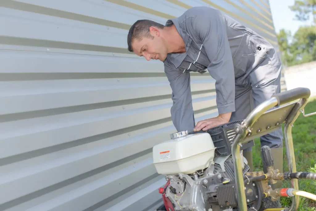 A man showing his pressure washer won't start outside his house. 