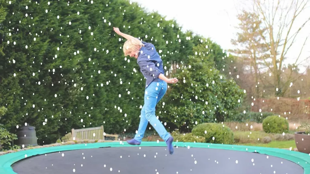 child jumping on trampoline in winter snow