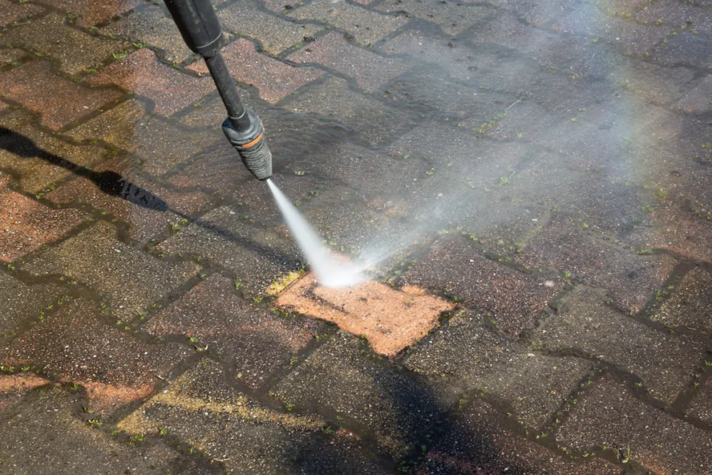 pressure washing driveway brick showing clean one next to dirty ones