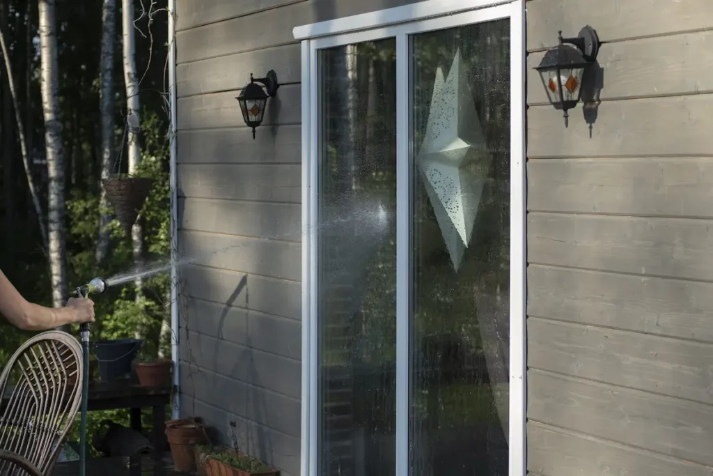 Pressure washing patio window in backyard