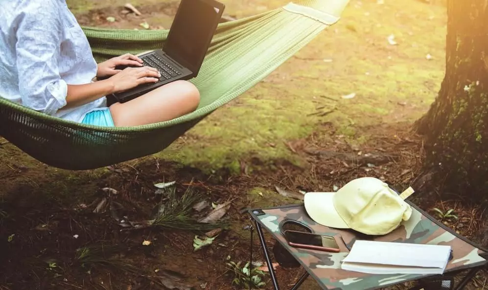 Person using a laptop on a hammock.